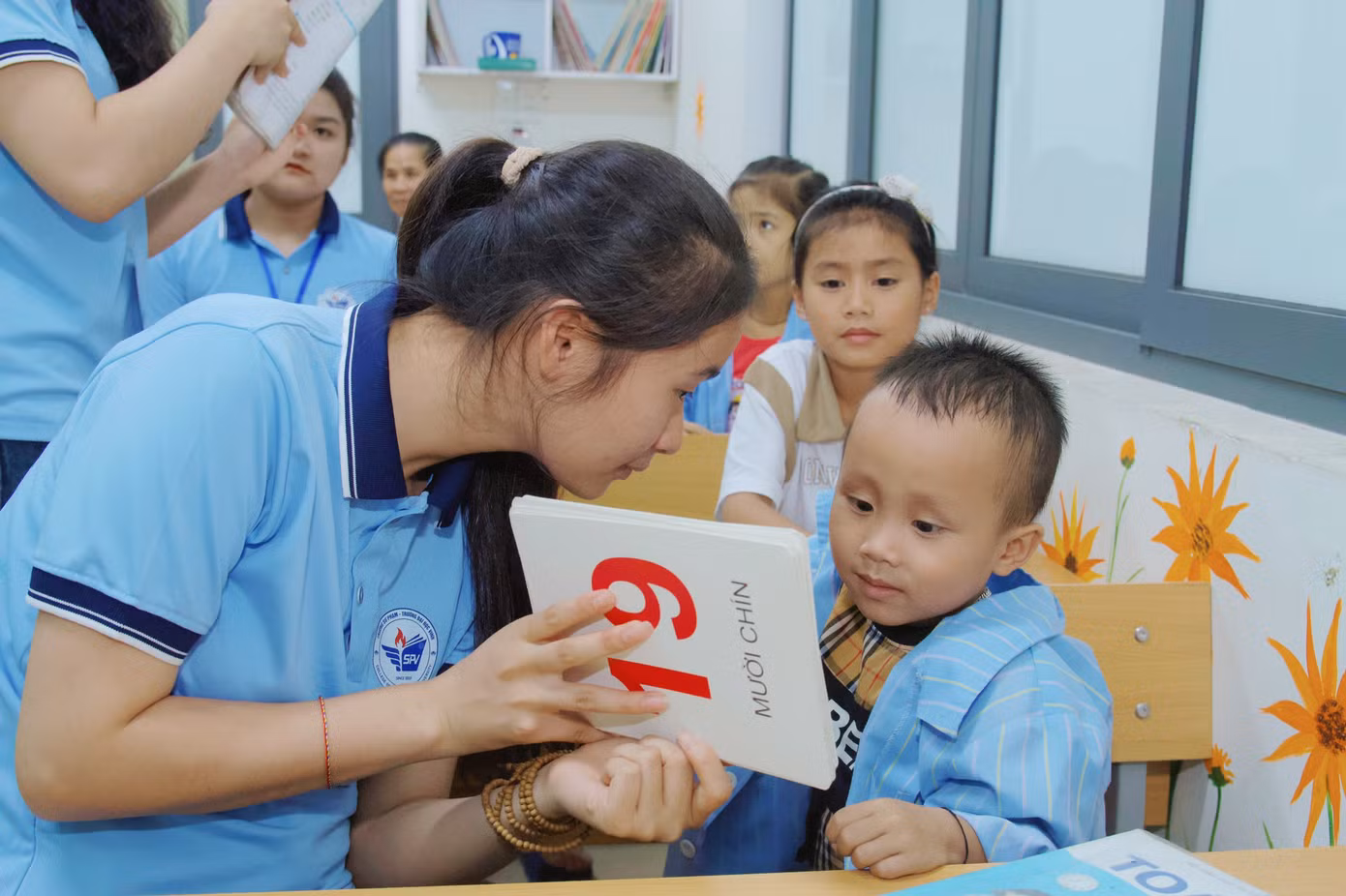 Tỉ mỉ chỉ cho một bé trai tập viết, bạn Lương Thị Nhược Hằng (SN 2003, lớp 62A4 Giáo dục tiểu học, Trường Đại học Vinh) cho biết, thành viên của lớp học không cố định, có khoảng gần 20 em với độ tuổi dao động từ khoảng 4 -10 tuổi và không cố định vì nhiều lý do.