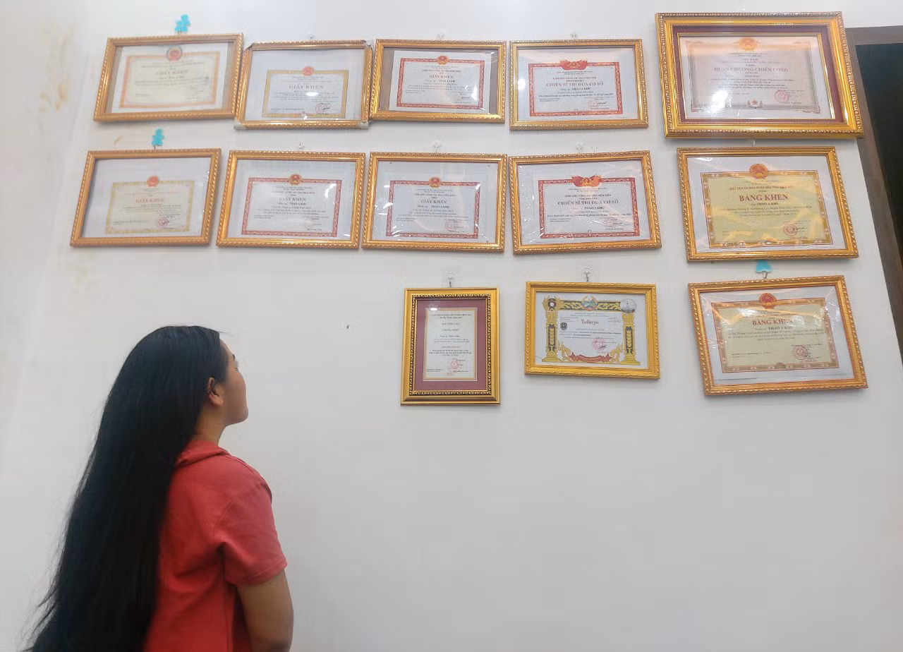 Chị Hờ T. D ngắm nhìn giấy khen, bằng khen mà Trung úy Thào A Khư nhận được sau quá trình nỗ lực triệt phá tội phạm ma túy.