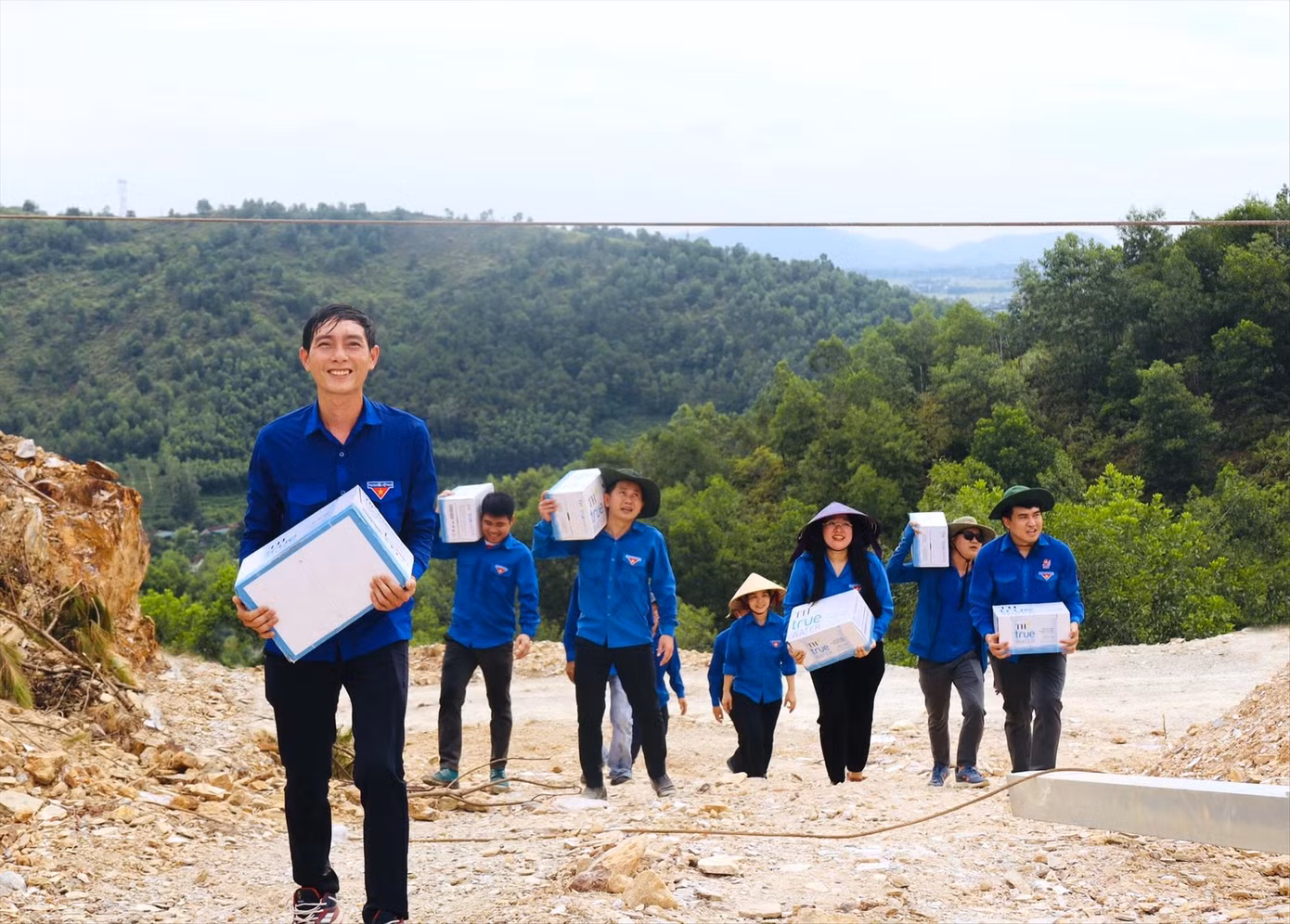 Các đoàn viên thanh niên vượt núi mang những thùng nước lên tiếp sức lực lượng thi công