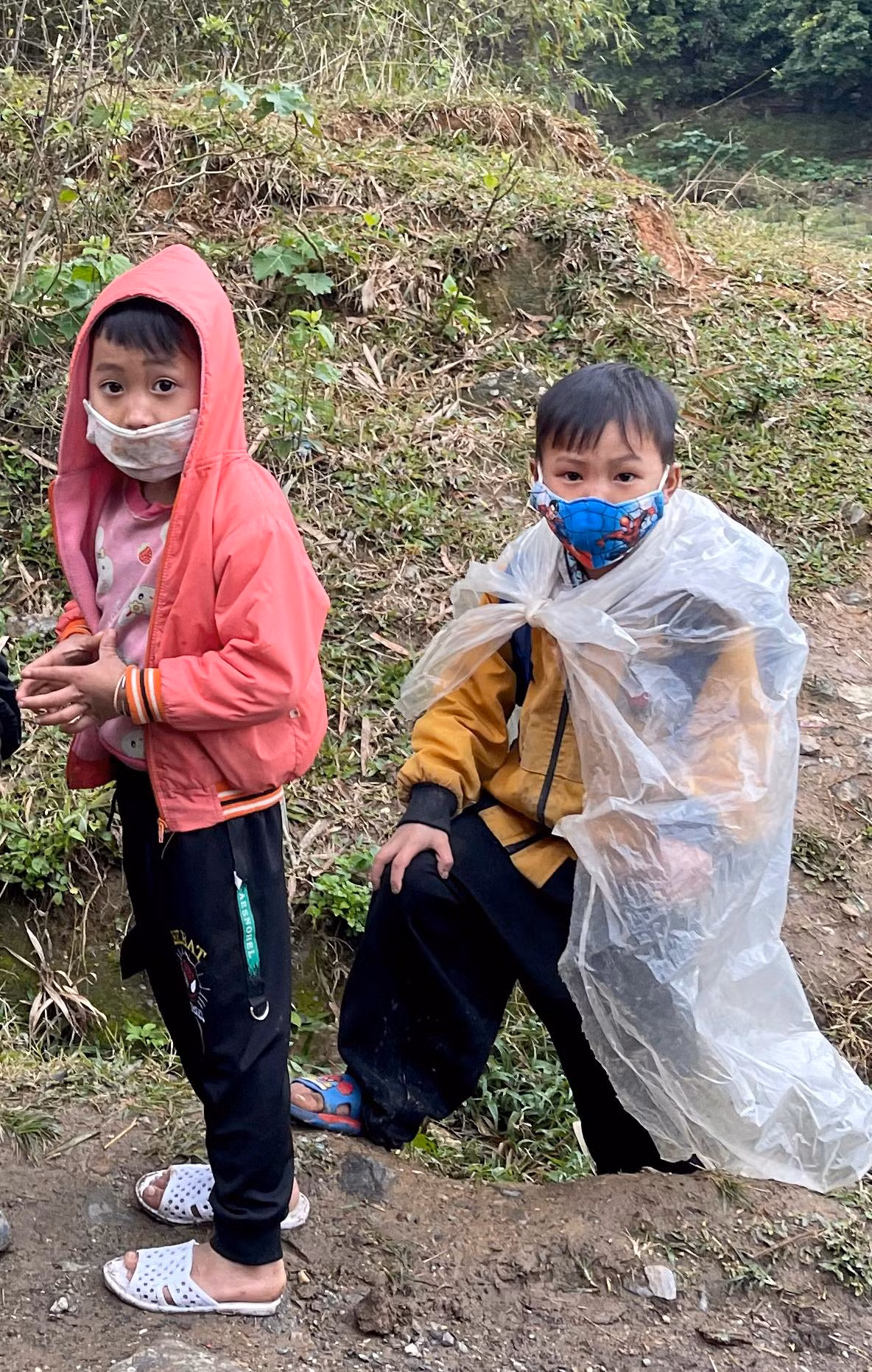 Trời rét buốt lạnh căm căm nhưng các em nhỏ vẫn đi dép lê, choàng áo mưa đi ngoài đường.