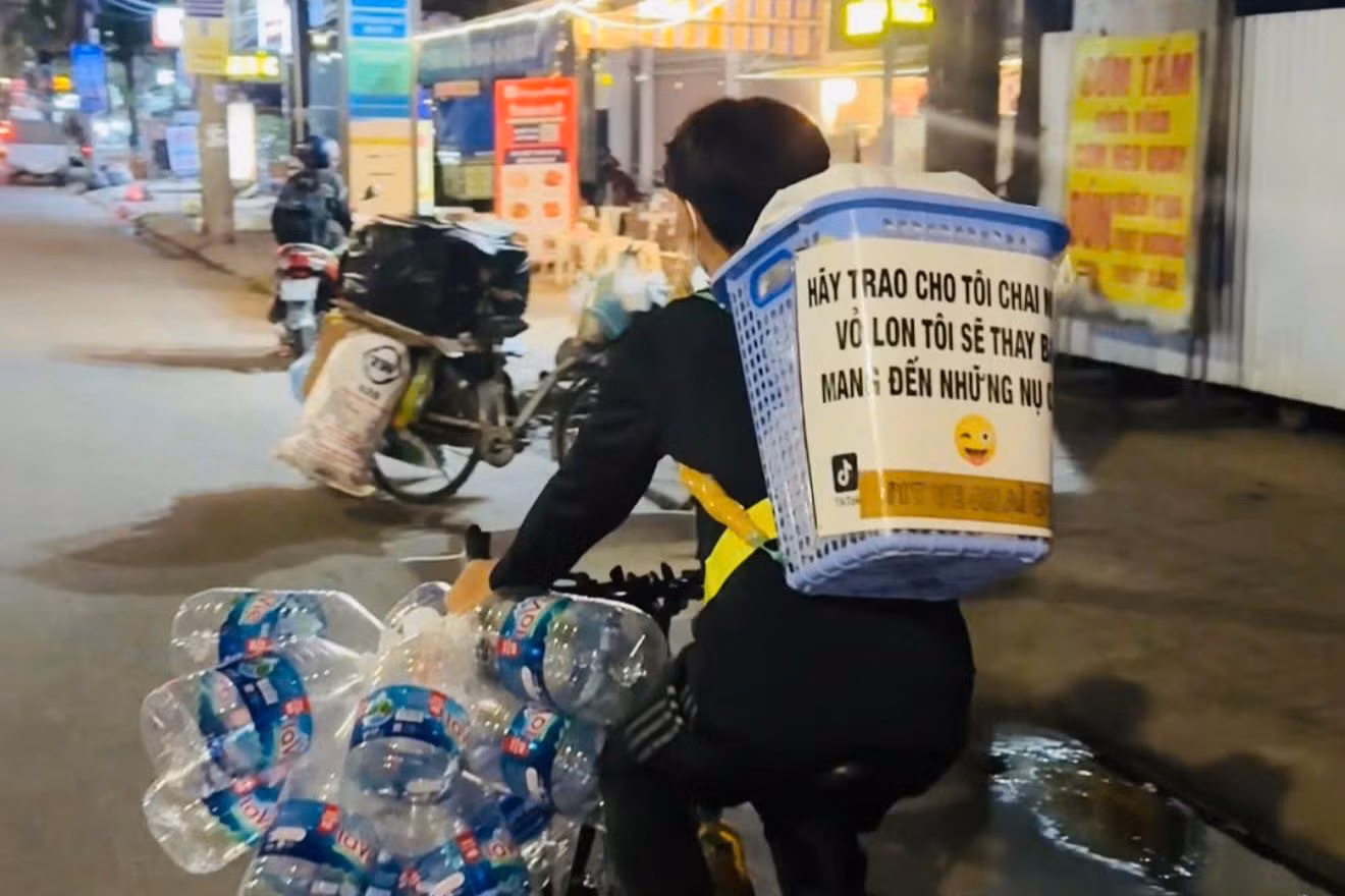 Chiếc xe đạp với dòng chữ “Hãy trao cho tôi chai nhựa, vỏ lon, tôi sẽ thay bạn mang đến những nụ cười”.