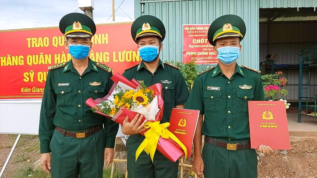 Đại tá Huỳnh Văn Đông (bên trái) - Chính ủy Bộ đội Biên phòng tỉnh Kiên Giang trao quyết định thăng quân hàm cho các sĩ quan tại chốt phòng, chống dịch.