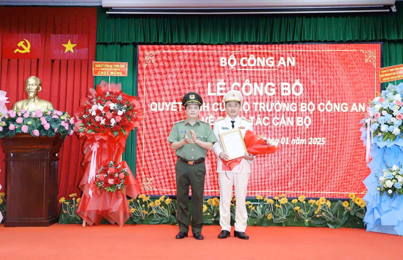 Thứ trưởng Bộ Công an Đặng Hồng Đức (trái) trao quyết định và tặng hoa chúc mừng đại tá Trần Văn Dương (phải).