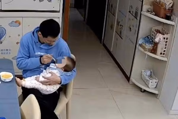 Anh Trần đang cho con gái nhỏ ăn bột. Ảnh: Baidu.