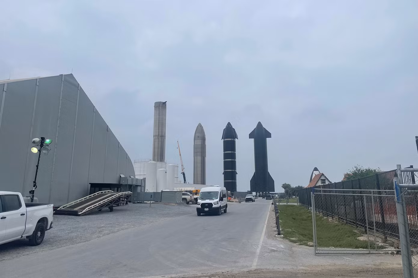 Một tên lửa đẩy và ba tàu vũ trụ Starship được xếp hàng gần các tòa nhà lắp ráp đồ sộ tại khu phức hợp Starbase của SpaceX ở Nam Texas. ( Ảnh: Jackie Wattles)