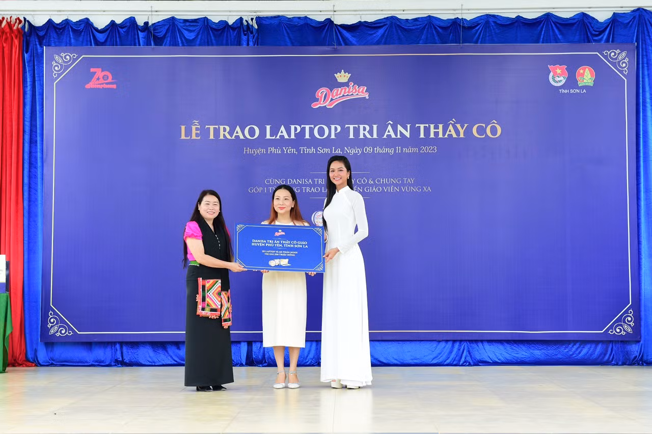 Hoa hậu H'Hen Niê và bà Phạm Thị Thu Thảo - Giám đốc Marketing nhãn hàng Danisa Việt Nam (ở giữa) trao tặng biểu trưng cho đại diện Phòng Giáo dục huyện Phù Yên, tỉnh Sơn La.