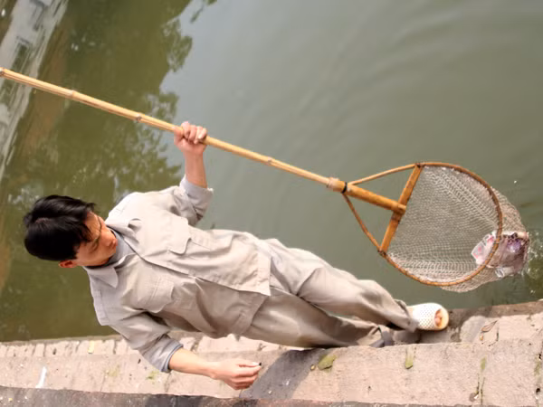Dùng vợt để dọn tiền dưới lòng hồ
