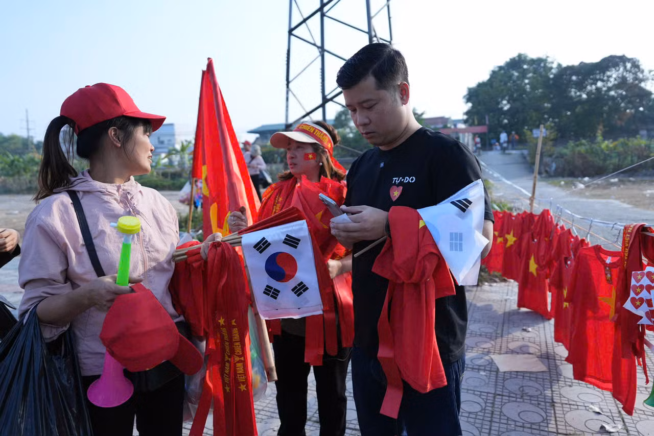 Khi giờ thi đấu diễn ra rất gần, khu vực bán đồ cổ vũ vô cùng sôi động, tấp nập khách ra vào.