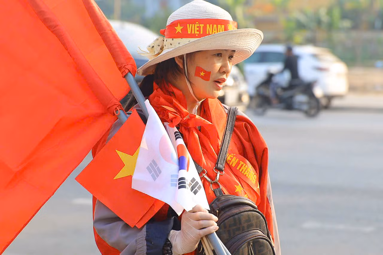 Cờ Tổ quốc là thứ không thể thiếu của người hâm mộ Việt Nam trong các trận đấu. Giống như thời HLV Park Hang-seo, khi HLV Kim Sang-sik dẫn dắt ĐT Việt Nam, bên cạnh lá cờ đỏ còn có cả cờ Hàn Quốc. Những lá cờ nhỏ được bán với giá 20.000 đồng, trong khi lá cờ to có giá 100.000 đồng.