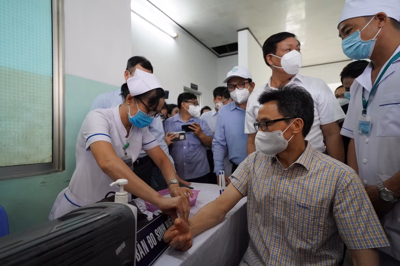 Nhân viên y tế đo huyết áp, kiểm tra sức khỏe Phó Thủ tướng Vũ Đức Đam trước khi tiêm chủng