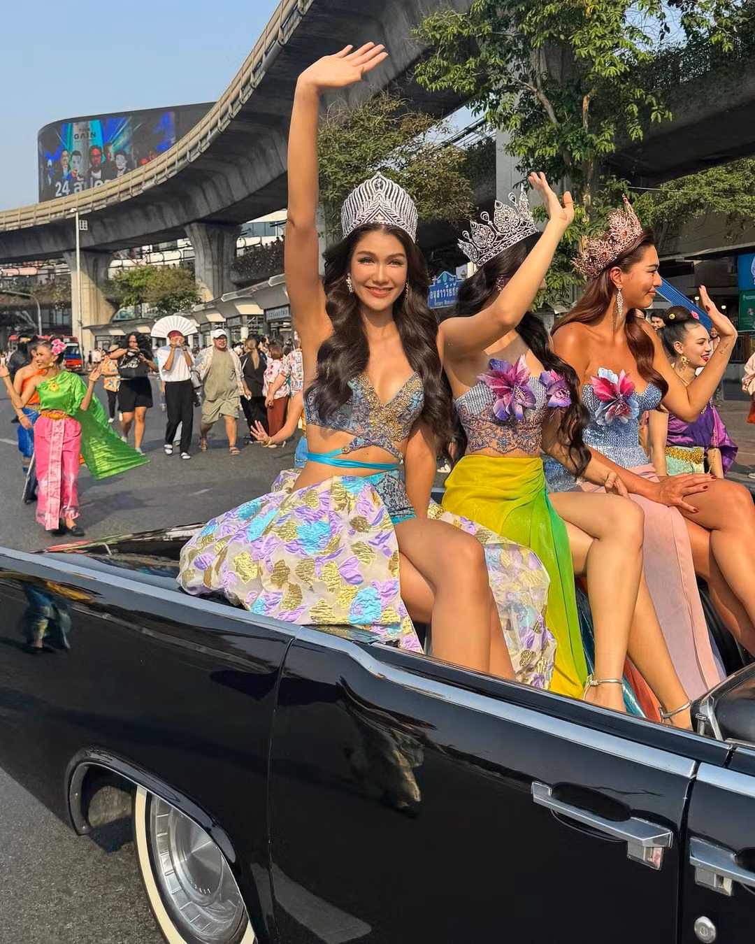 Hoa hậu Hoàn vũ Thái Lan 2021 Anchilee Scott-Kemmis, Hoa hậu Hoàn vũ Thái Lan 2015 Aniporn Chalermburanawong, Hoa hậu Hoàn vũ Thái Lan 2016 Namtan Chalita Suansane diện trang phục rực rỡ, nổi bật khi ngồi trên xe diễu hành.