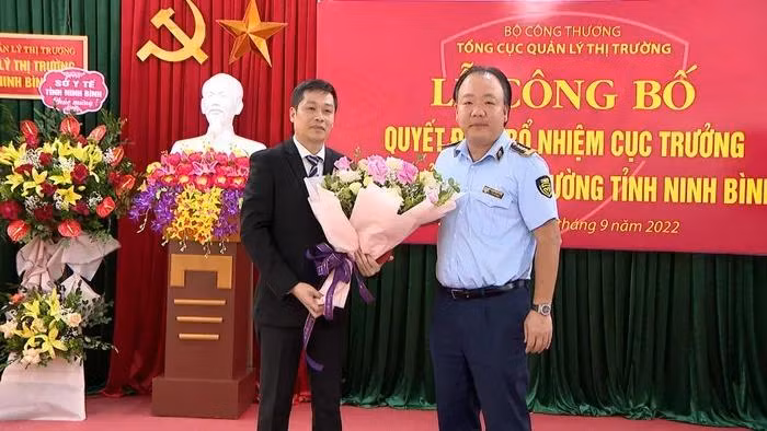 Ông Trần Hữu Linh Tổng cục trưởng Tổng cục Quản lý thị trường trao Quyết định và hoa cho Tân Cục trưởng Cục QLTT Ninh Bình Phan Thế Anh. Ảnh: Công thương