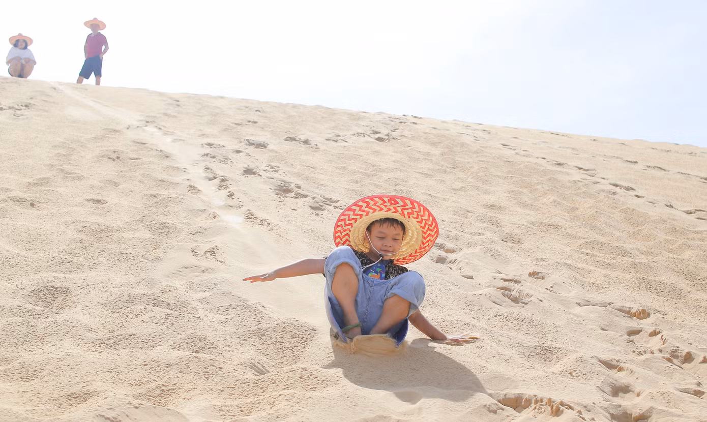 Các em nhỏ thích thú chơi trượt cát. Ảnh: Trương Định.