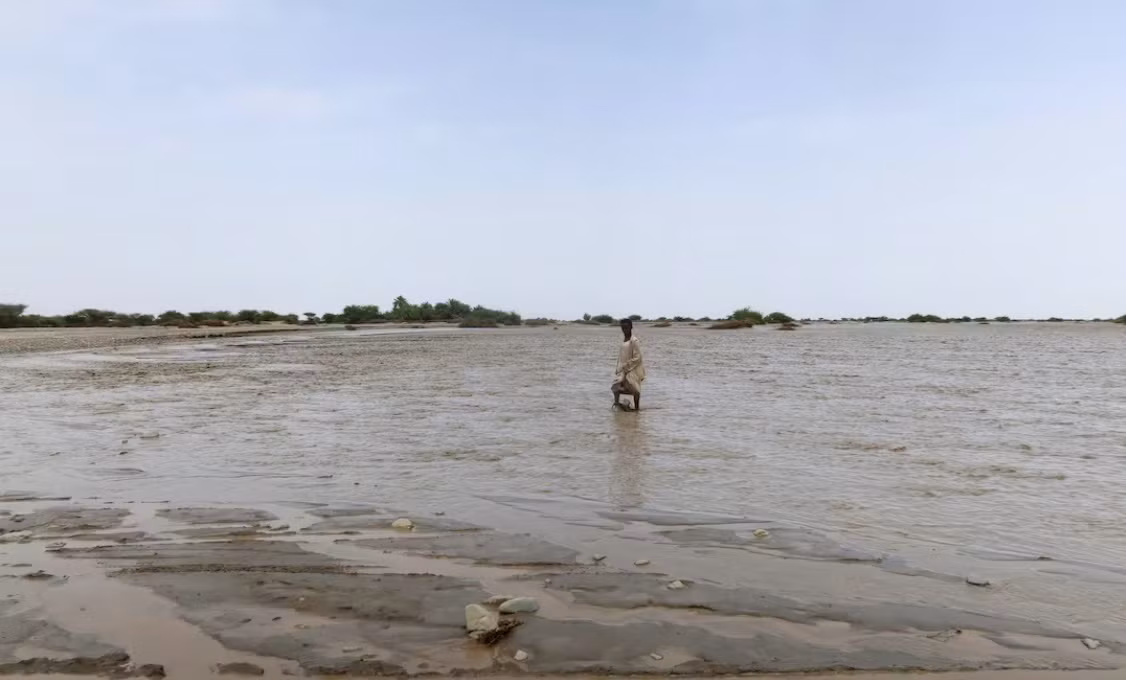 Một người lội giữa bãi bùn ở Port Sudan ngày 26/8. (Ảnh: Reuters)