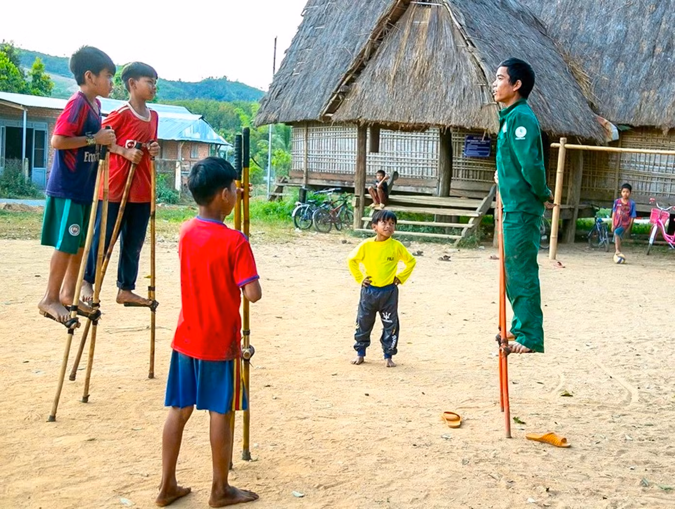 Anh Tham phô diễn kỹ năng đứng trên cà kheo với các em nhỏ.