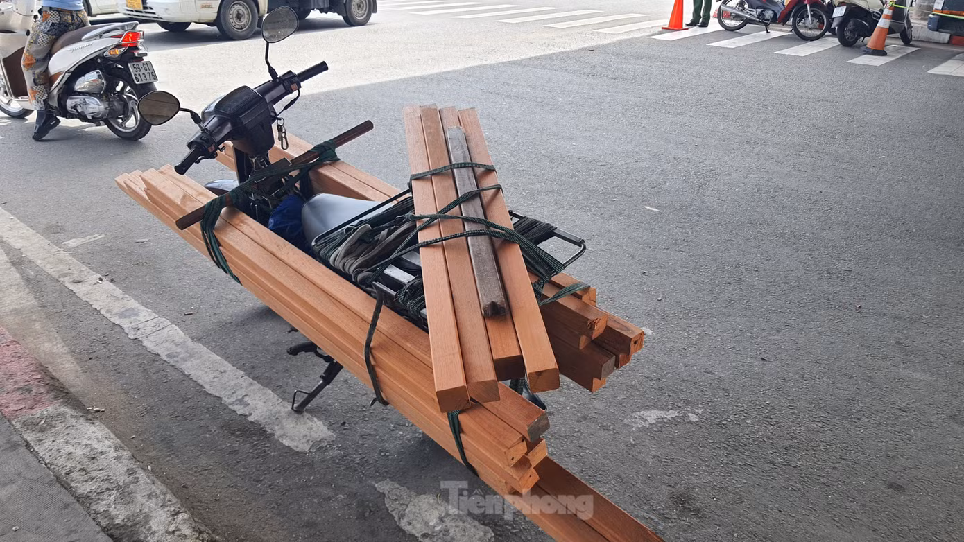 Ông T. chất đầy thanh gỗ dài cặp bên hông xe để giao cho khách. Ảnh: Hoàng Thuận.