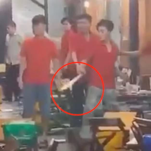 Nam nhân viên cầm mã tấu đe dọa khi thấy đồng nghiệp bị ném ly bia (Ảnh cắt từ clip).