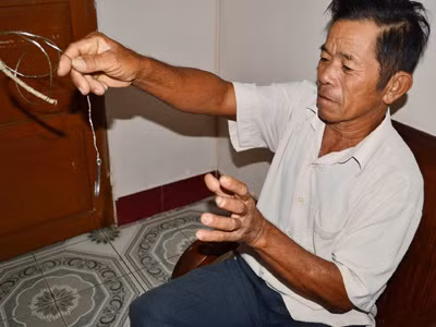 Lão ngư Lê Văn Ba diễn tả lại động tác thả mồi câu theo dàn câu nhiều lưỡi