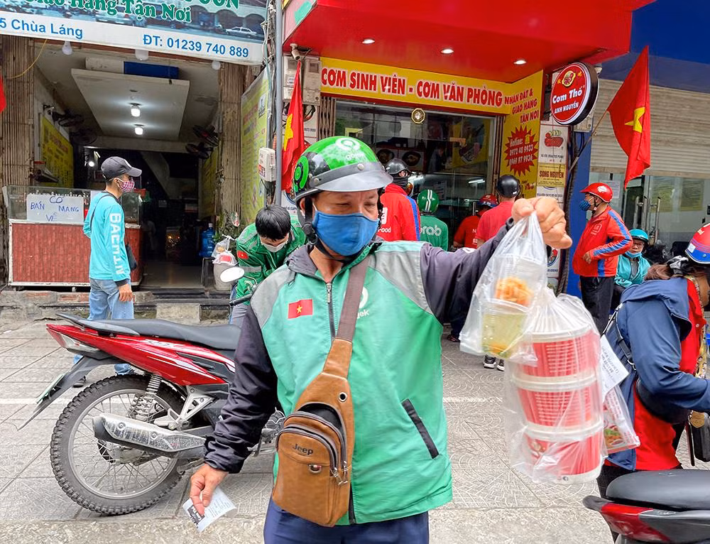 Từ khoảng 11h30 - 12h30 là thời điểm hàng quán đông khách nhất. Shipper có thời điểm chờ tới 20 phút để lấy đồ. Làm việc mùa dịch, cả chủ quán, nhân viên, shipper chủ động đeo khẩu trang, găng tay, ...