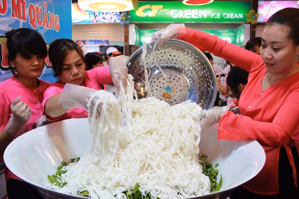 Rồi cho mì Quảng rải đều và tạo điểm nhọn trên tô