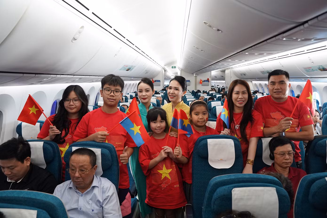 Tất cả hành khách cùng phi hành đoàn vẫy cao lá cờ đỏ sao vàng, hòa mình vào giai điệu bài hát “Như có Bác trong ngày đại thắng” trên chuyến bay. Ảnh: VNA.