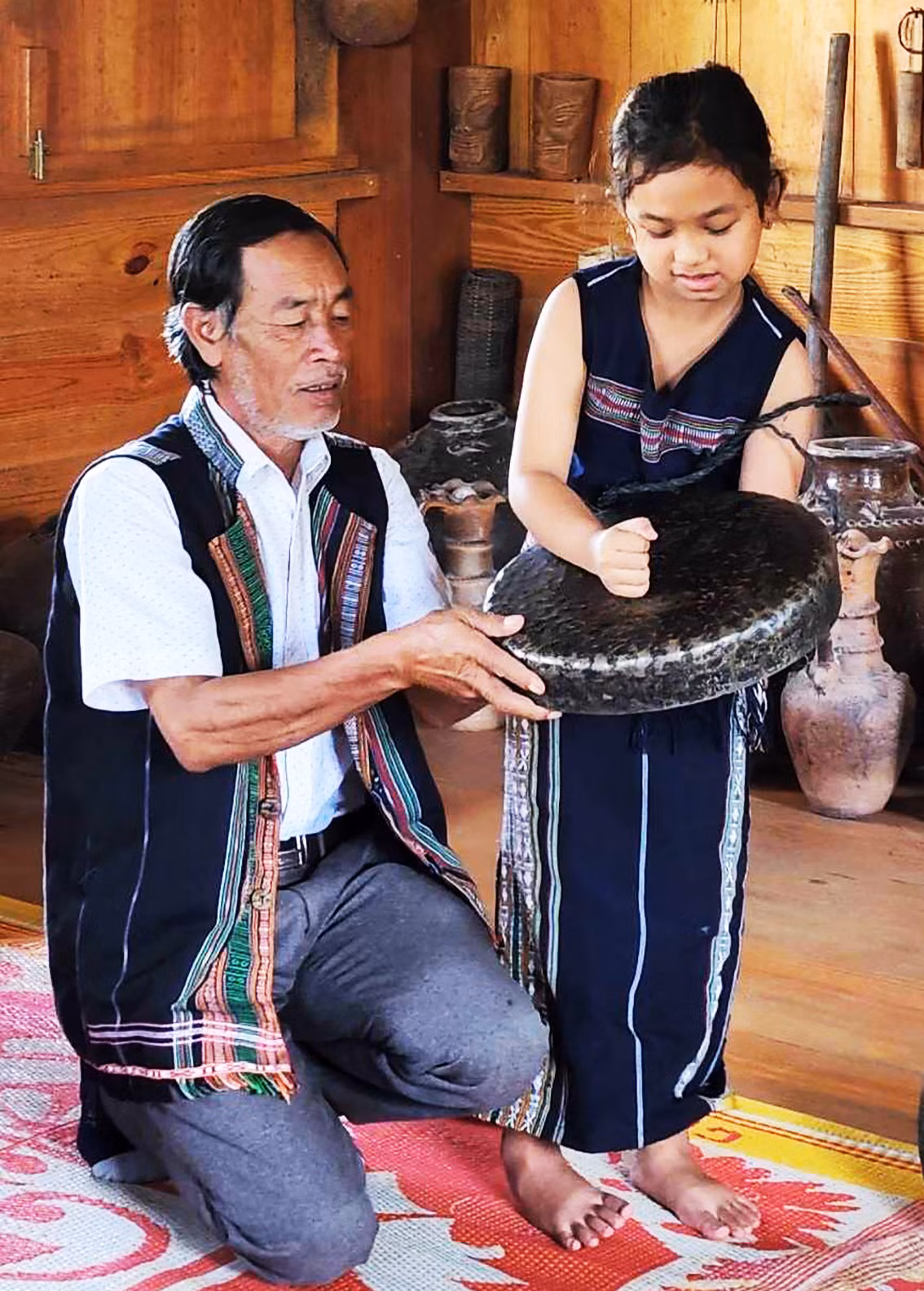 Ông K’Bes dạy bé gái đánh chiêng. Ảnh: Chế Phương Nam