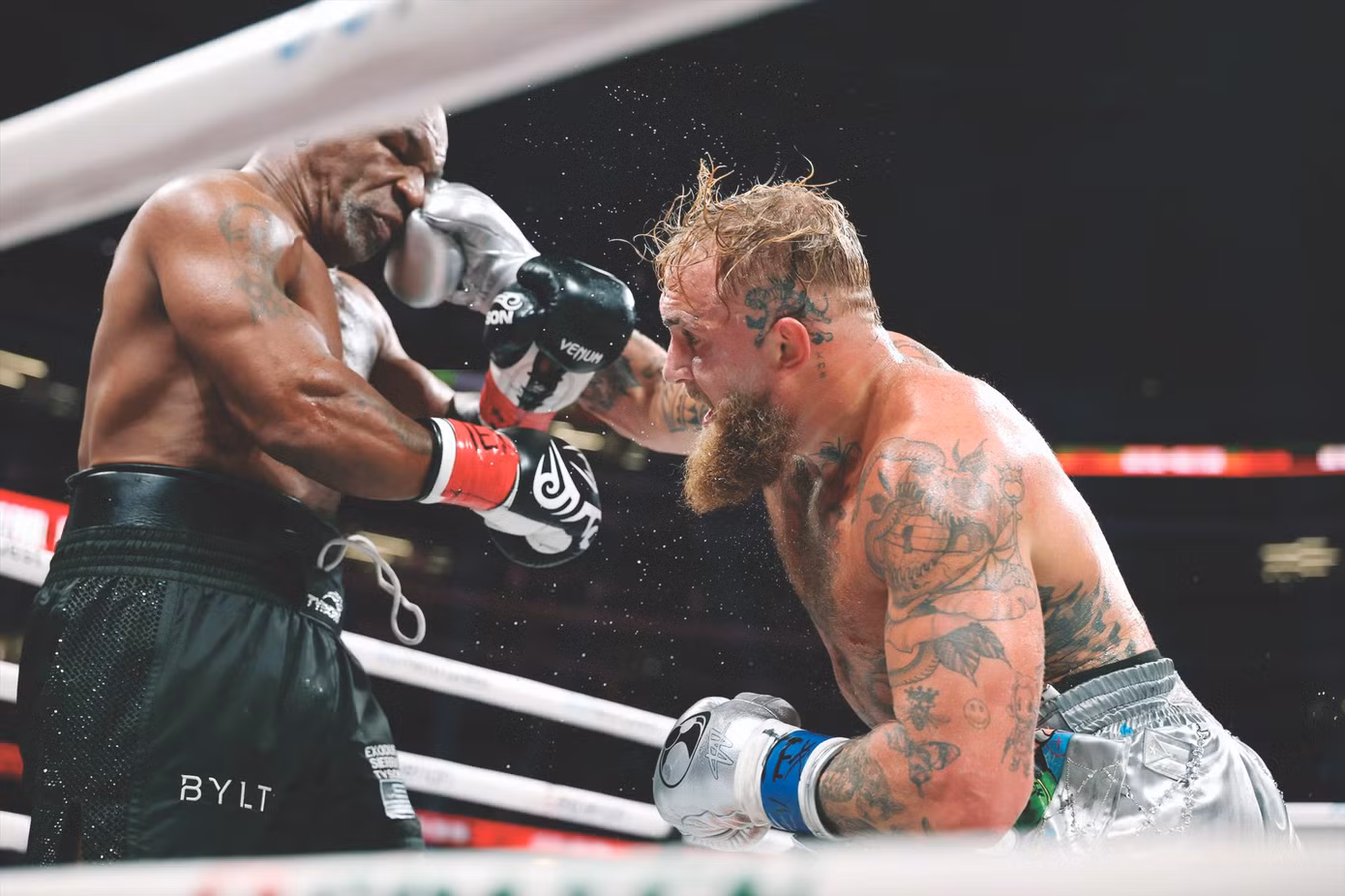 Mike Tyson (trái) chịu đựng cú đấm của đối thủ. Ảnh: Getty Images