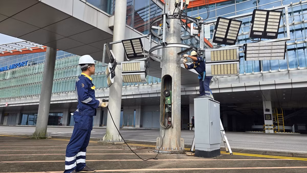 Đội ngũ kỹ thuật của sân bay Vân Đồn đang cho hạ toàn bộ hệ thống đèn chiếu sáng trên cao ngoài sân đỗ đồng thời cố định lại bằng dây thép.