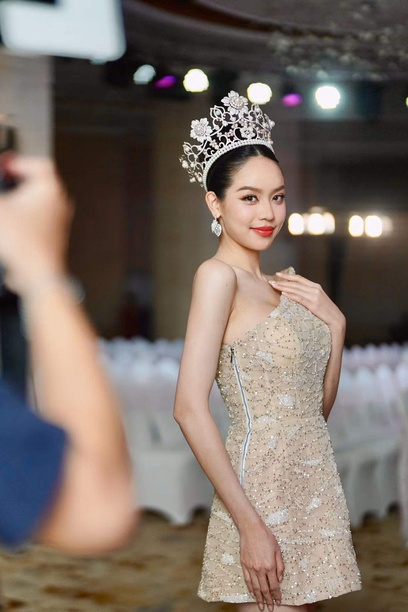 Thanh Thủy diện bộ váy sequin lệch vai màu nude trong buổi giao lưu. Thiết kế giúp người đẹp khoe vai trần thon thả, tôn lên vóc dáng thanh mảnh.