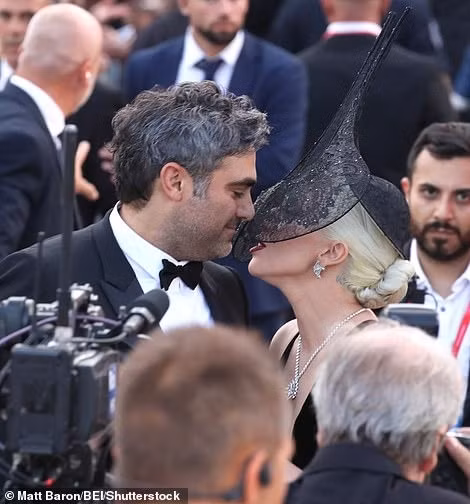Bất chấp vẻ ngoài xấu xa, Lady Gaga không thể che giấu được thực tế là cô đang sống trong giai đoạn nồng cháy nhất của tình yêu. Người đẹp 8X không ngần ngại thể hiện tình cảm với doanh nhân sinh năm 1978 trước ống kính máy ảnh. Hai người trao nhau nụ hôn nhẹ trên thảm đỏ. Ảnh: Shutterstock.