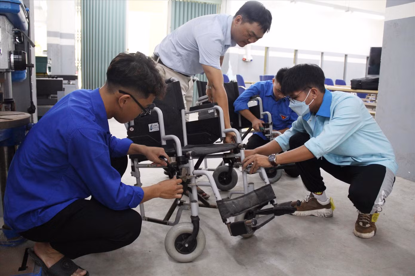 Những “thợ áo xanh” của Đoàn Trường Cao đẳng Nghề Đà Nẵng đang sửa chữa chiếc xe lăn hư hỏng Ảnh: Giang Thanh