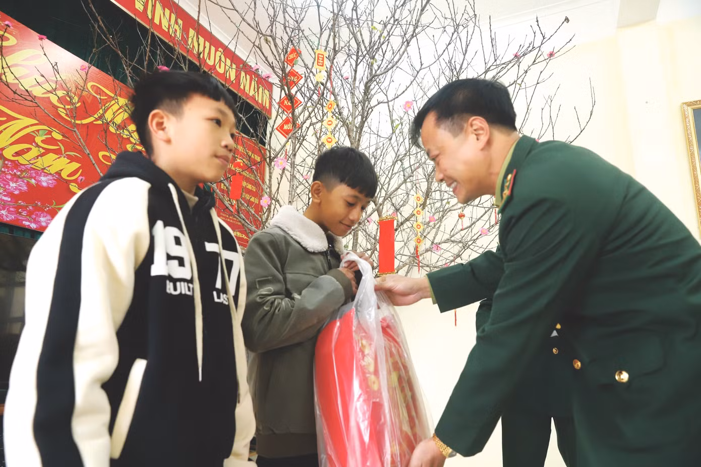 Trung tá Bùi Anh Đức, Đồn trưởng Đồn Biên phòng đảo Trần trao quà Tết cho 2 cháu trong Chương trình “Con nuôi đồn biên phòng - Nâng bước em tới trường”