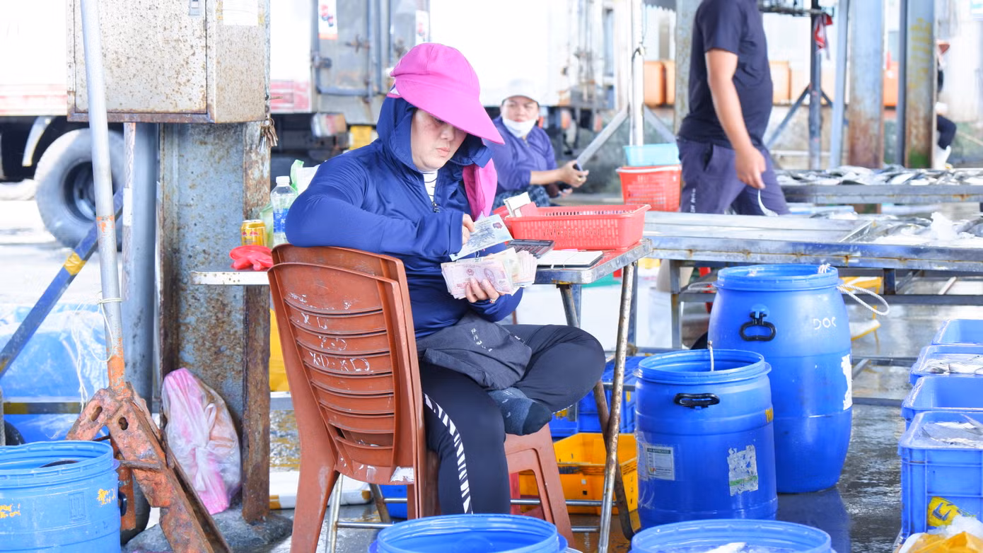Tiểu thương, chủ tàu thu tiền bán hải sản ngay tại chợ cảng cá Thọ Quang. (Ảnh: Nguyễn Thành)