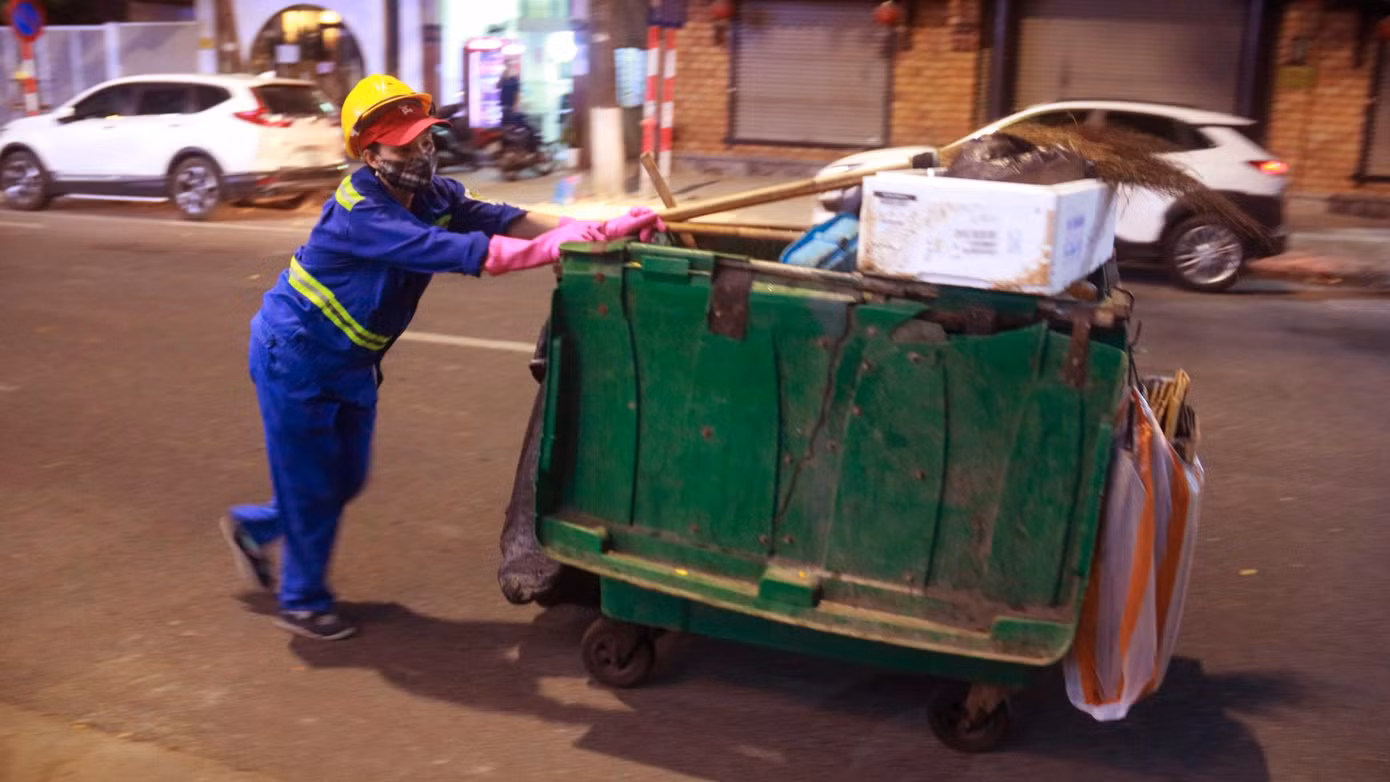 Nữ lao công quét rác vẫn âm thầm làm việc giữa phố phường vắng lặng không bóng người.