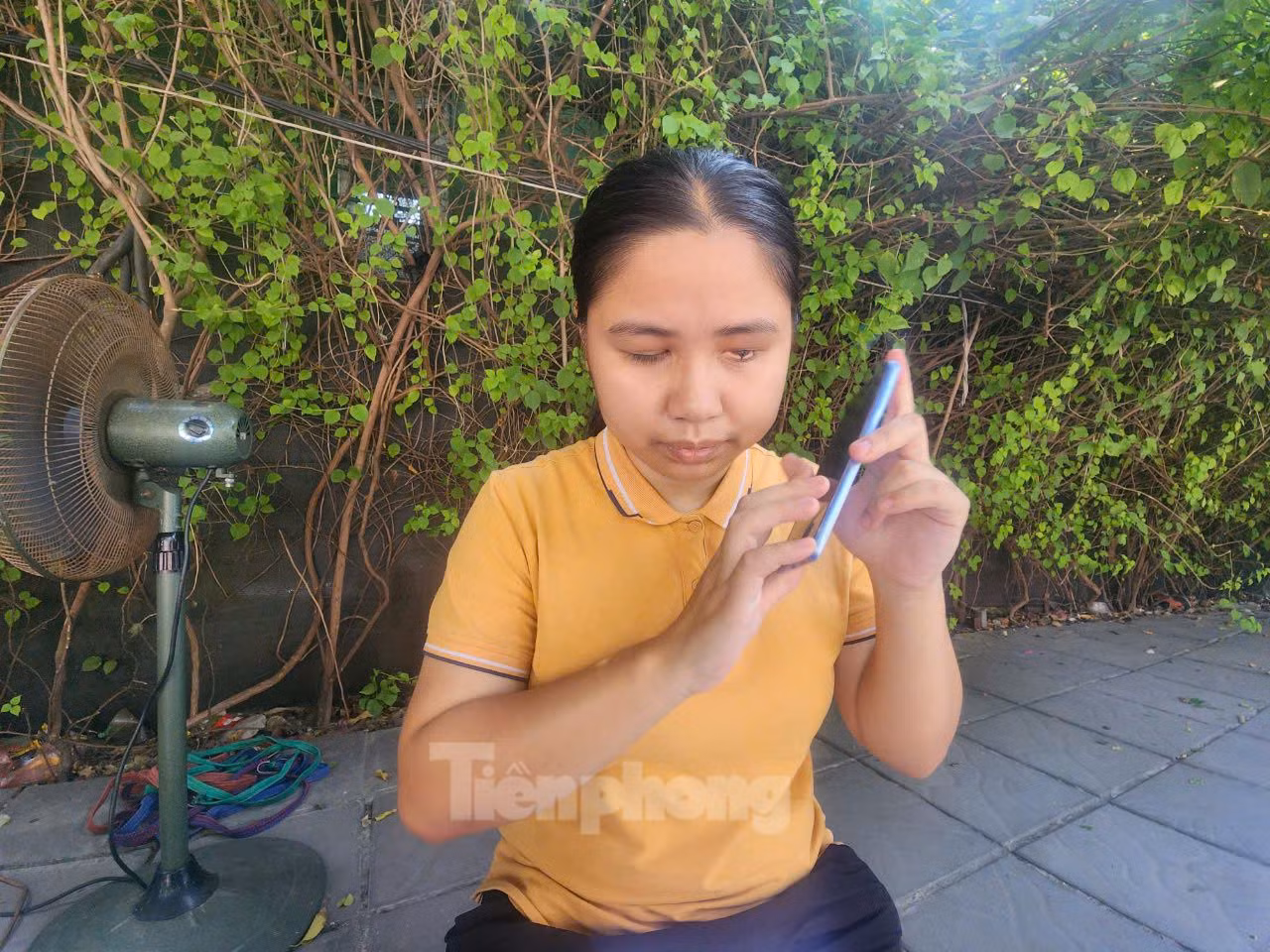 Nguyễn Thị Minh nghe âm thanh trên điện thoại để tìm hiểu thông tin