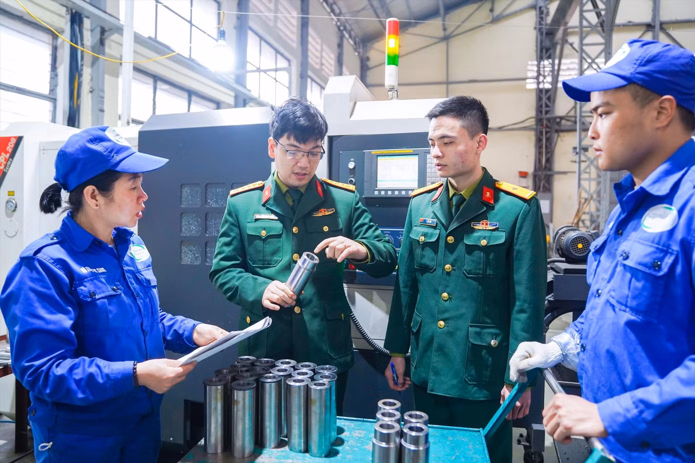 Đại úy Trần Minh Tuyên (thứ hai từ trái qua) hướng dẫn quy trình công nghệ gia công vỏ đầu đạn cao xạ cho công nhân nhà máy Z183