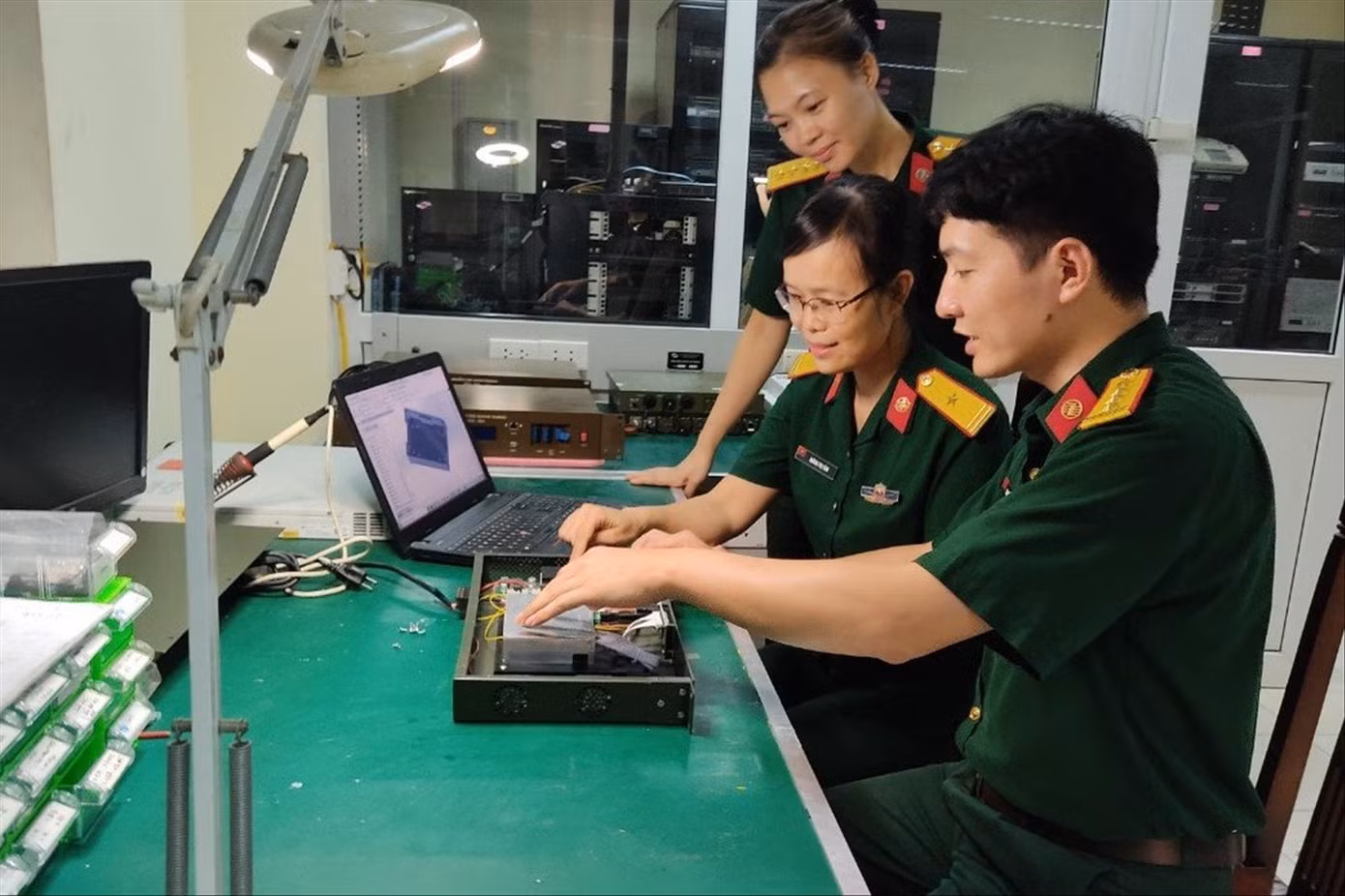 Đại úy Nguyễn Mạnh Toàn (ngoài cùng bên phải) trao đổi với đồng đội cách khai thác, sử dụng bộ khuếch đại quang EDFA