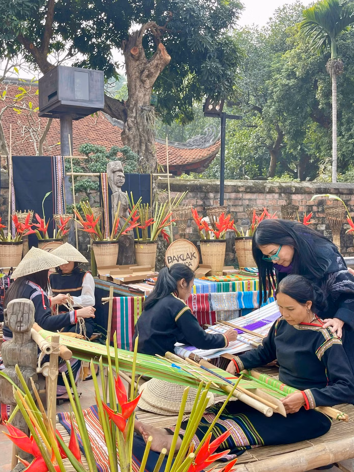 NTK Minh Hạnh (kính xanh) và các nghệ nhân. Món quà tặng là quạt cói Kim Sơn Ninh Bình và túi thổ cẩm khiến nhiều người thích thú. Ảnh: Hoàng Tú.