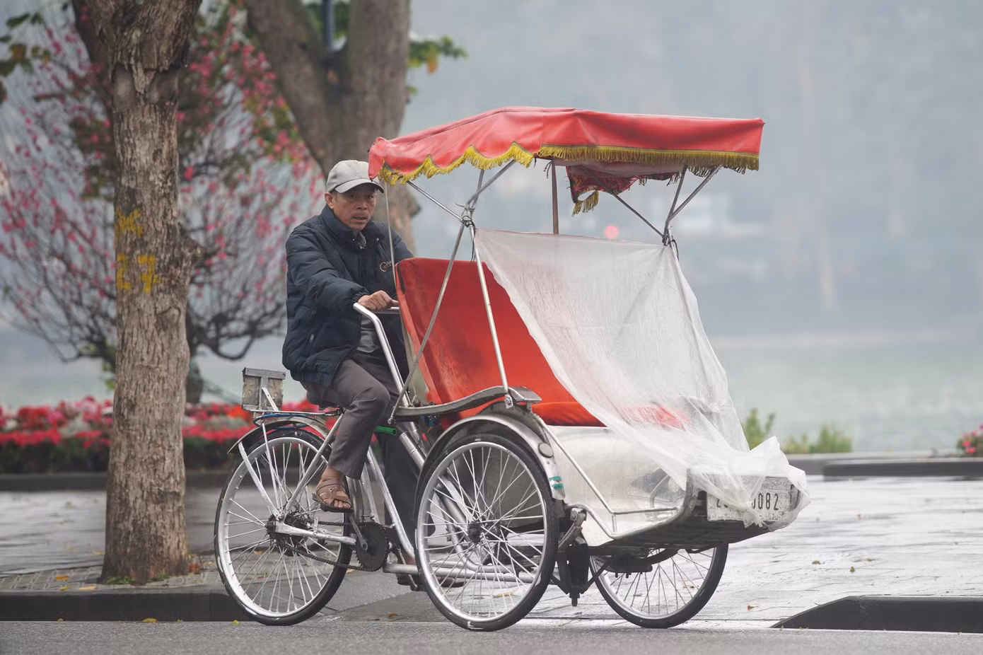 Xích lô dùng bạt che mưa chỗ ngồi trước khi đón khách.