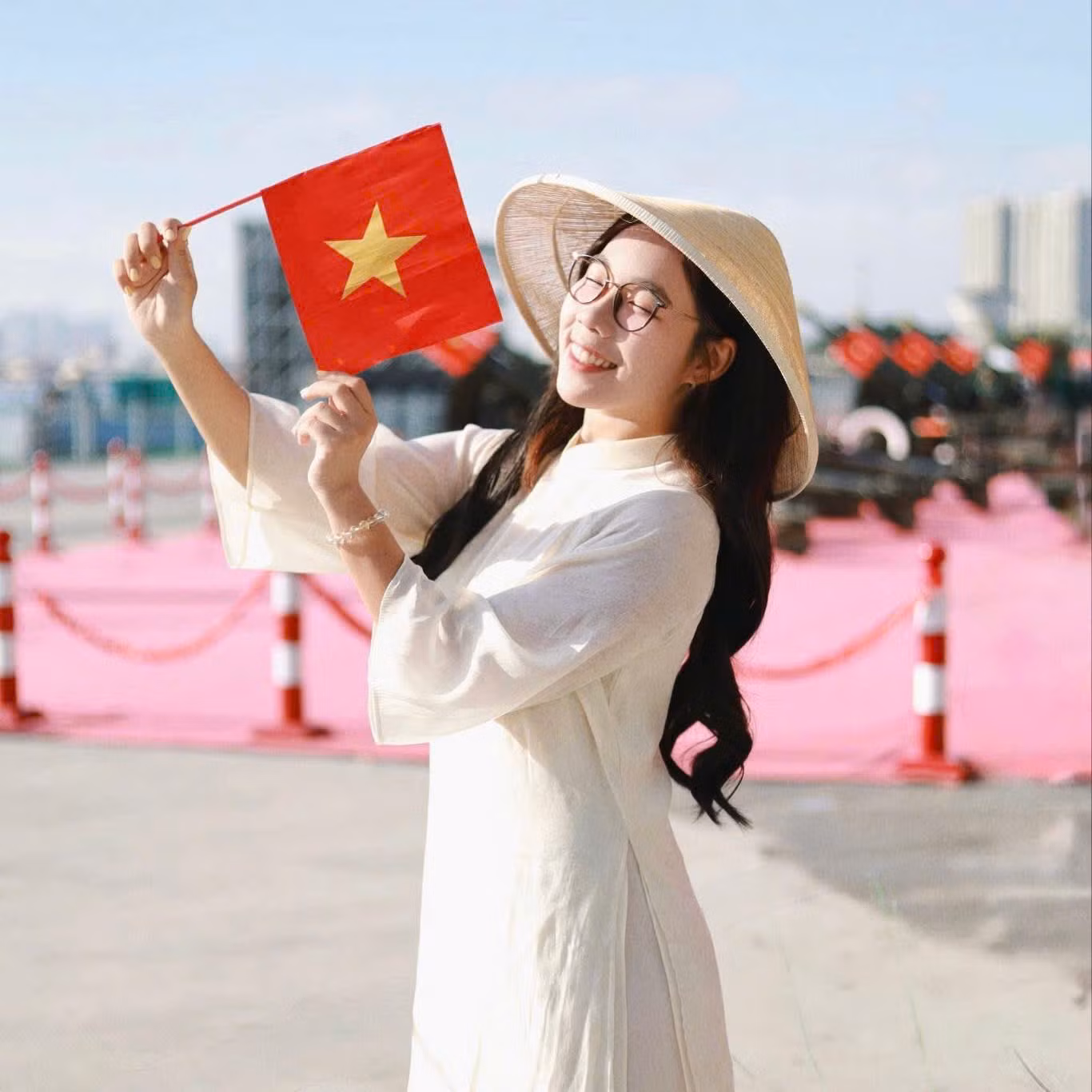Thùy Linh chọn ảnh đại diện Facebook diện áo dài trắng, đội nón lá, tay cầm cờ đỏ sao vàng chụp ảnh cùng dàn pháo lễ tại bến Bạch Đằng (Q. 1, TP. HCM) (Ảnh: 'Linh thích chụp ảnh')