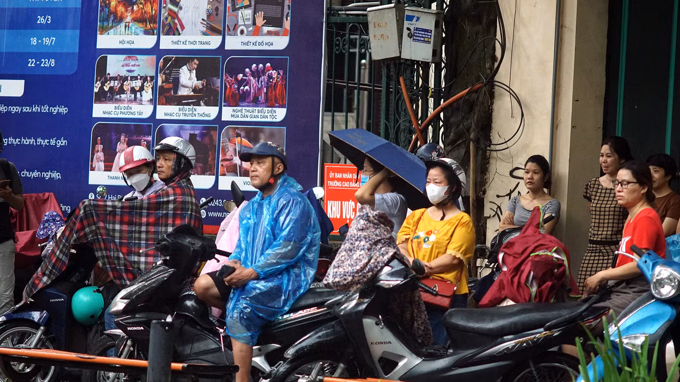 Nhiều phụ huynh đội mưa chờ con ngoài điểm thi.