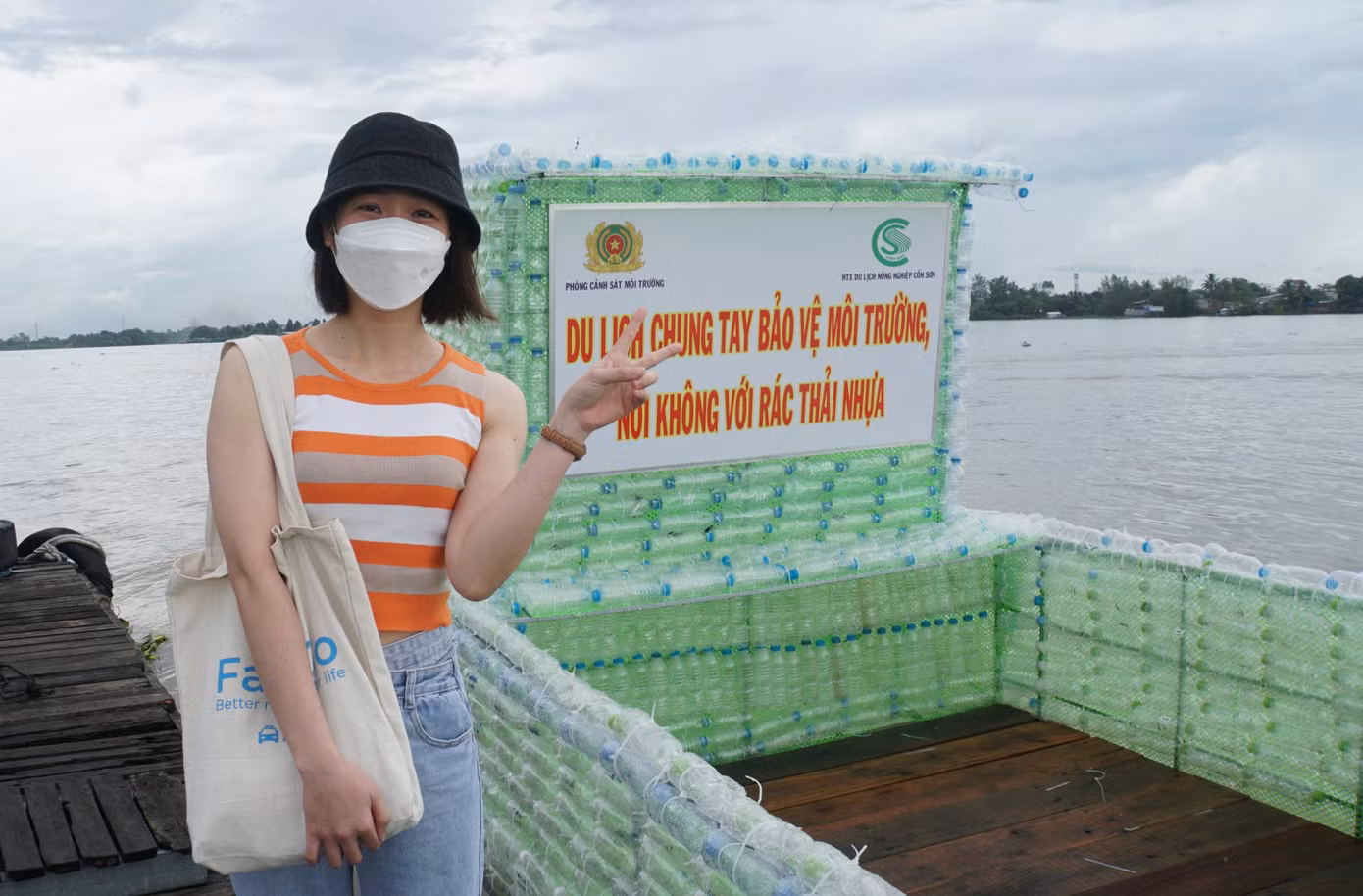 Bạn Nguyễn Thị Thu Thảo chụp ảnh lưu lại kỷ niệm bên chiếc thuyền bằng chai nhựa. - Ảnh: Hòa Hội