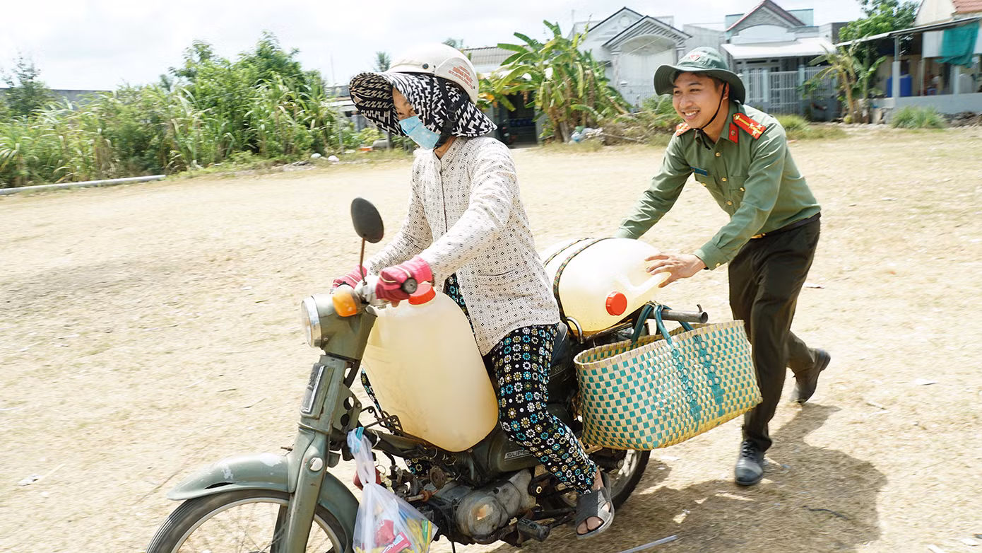 Chiến sĩ công an Bến Tre hỗ trợ bà con đẩy xe chở nước giữa trưa nắng. Ảnh: Hòa Hội