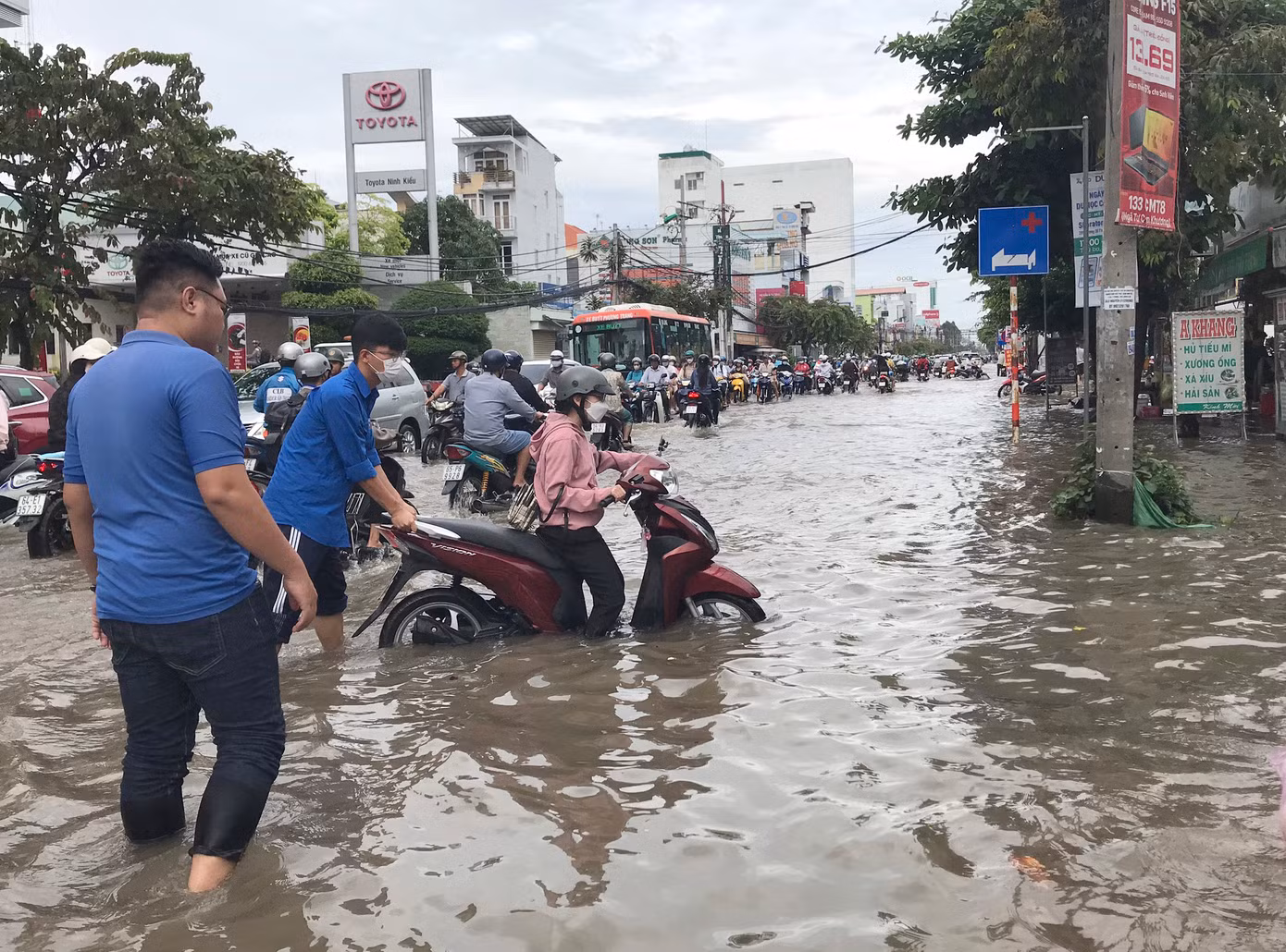 Đoàn viên thanh niên hỗ trợ người dân đẩy xe vượt qua đoạn bị ngập sâu.