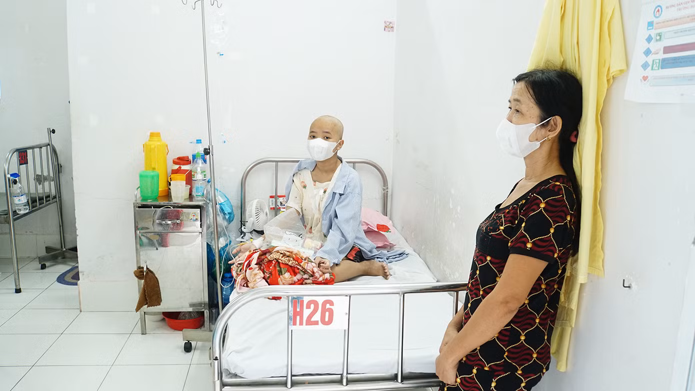Bà Nguyễn Thị Tr. đứng bên cạnh con gái - Trương Thị Tr.L., sinh viên năm 3, Trường Đại học Cần Thơ (quê ở An Giang). Tr.L. bị ung thư máu đang điều trị tại bệnh viện. “Gia đình tôi nghèo, có 2 đứa con. Chồng đi làm thuê, con trai lớn nghỉ học ở nhà phụ hồ. Con gái đang học đại học bỗng phát hiện ung thư máu cách nay hơn 2 tháng rồi vô đây điều trị. Hằng ngày, gia đình làm thuê để gửi tiền xuống lo con chữa trị”, bà Tr. nói. Ảnh: Hòa Hội.