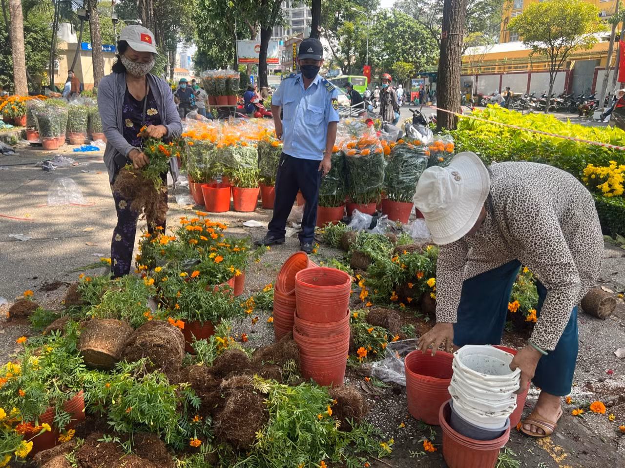 Hoa bị phá bỏ, tiểu thương chỉ lấy lại chậu. Hoa nằm ngổn ngang trên mặt đất.