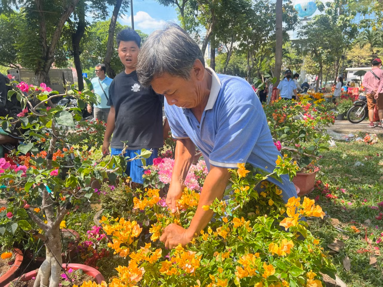 Lúc 12 giờ trưa, tiểu thương kinh doanh hoa Tết tại công viên 23/9 (quận 1) tự cắt bỏ hoa chứ không giảm giá, bán rẻ.