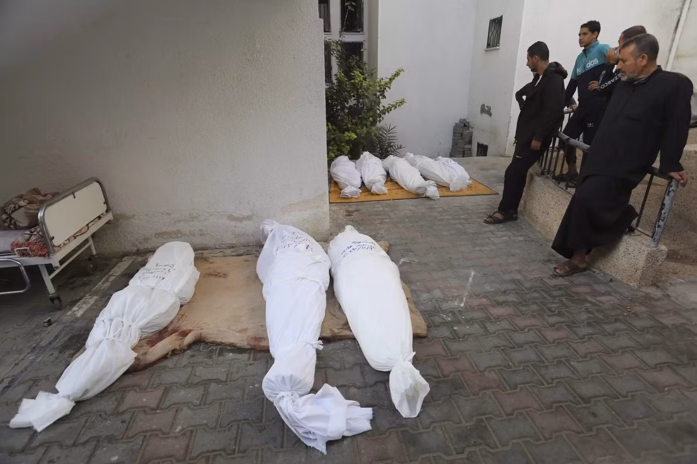 Người dân Palestine đứng bên các thi thể của một gia đình thiệt mạng trong vụ không kích của Israel vào Dải Gaza.