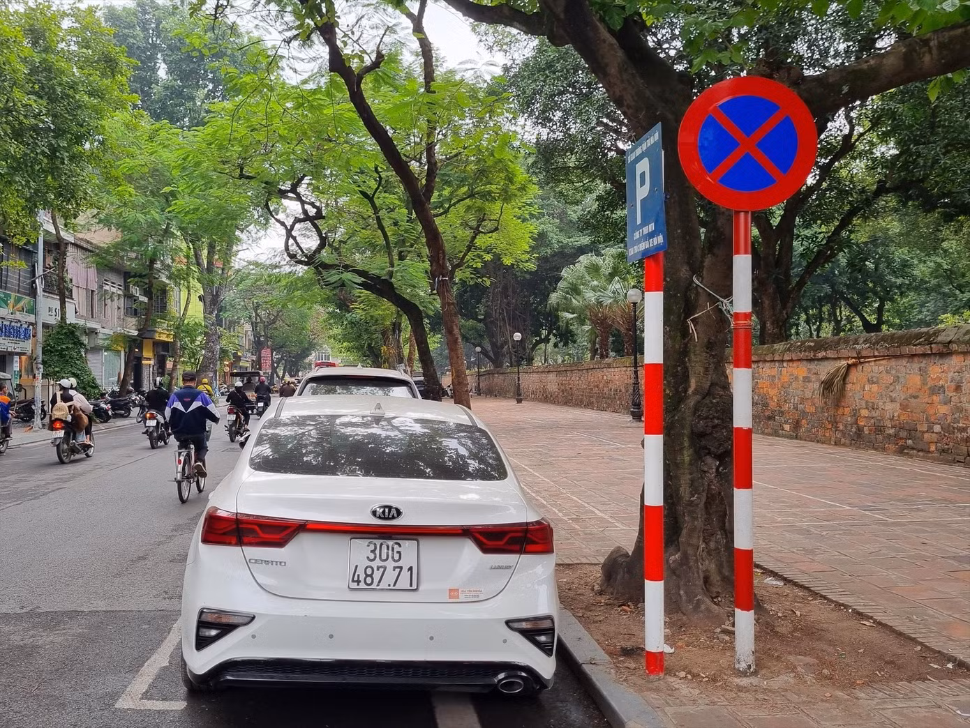 Biển báo cấm dừng đỗ cắm cạnh biển thông báo điểm trông giữ xe. Ảnh: Viết Hà.