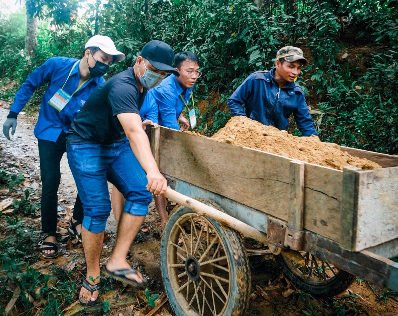Khi vận chuyển vật liệu vào nơi tập kết thì trời đổ mưa, đường trơn trượt nên việc vận chuyển mất khá nhiều thời gian. Mọi người phân công nhau tìm đồ đậy che đậy xi măng cho khỏi ướt, người khuân vác đồ chạy thật nhanh, nhóm kéo xe cát căng sức đẩy...
